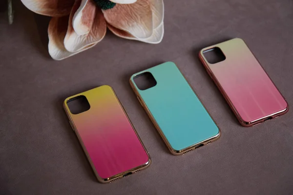 beautiful womens mobile phone cases on the background of artificial flowers shimmer with a gradient shine