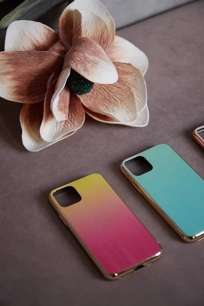 beautiful womens mobile phone cases on the background of artificial flowers shimmer with a gradient shine