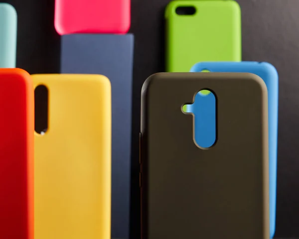 Estojos coloridos para smartphones modernos estão em stands na mesa um objeto em foco desfocado fundo — Fotografia de Stock