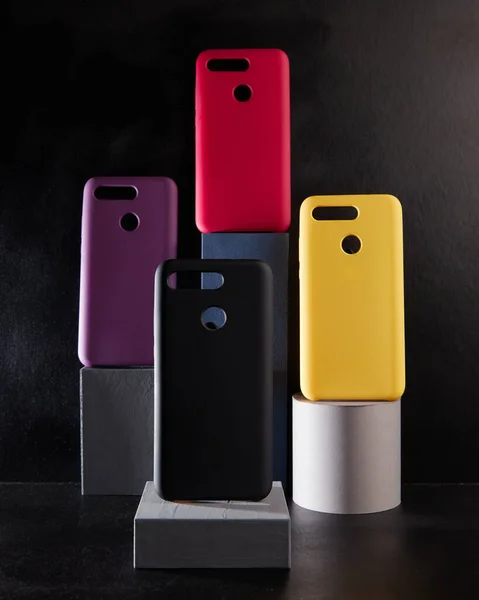 Casos coloridos para smartphones modernos ficar em stands na vista lateral da mesa desfocado fundo — Fotografia de Stock