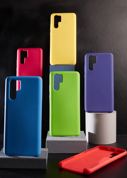 Casos coloridos para smartphones modernos ficar em stands na vista lateral da mesa desfocado fundo — Fotografia de Stock