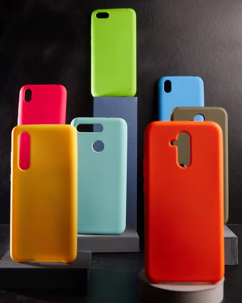 Colorful cases for modern smartphones stand on stands on the table side view blurred background — Stock Photo, Image