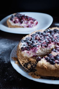 Mutfaktaki masada hazırlanmış meyveli turta. Aşçı, bulanık bir arkaplandan bir parça keser.