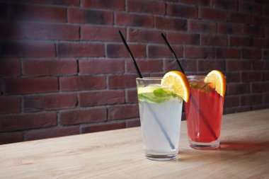 Masada, meşrubatlar, çeşitli kokteyller, kamışlı bir bardak ve bir dilim limon, bulanık bir arka plan.