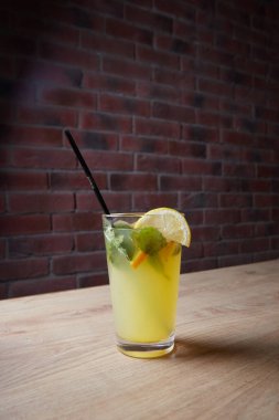 Masada, meşrubatlar, çeşitli kokteyller, kamışlı bir bardak ve bir dilim limon, bulanık bir arka plan.