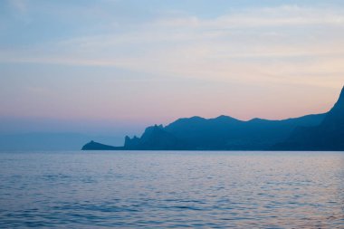 Gün batımında kaya ve deniz, akşam ışığı, gölgedeki dağlar, karanlıktaki manzara denizi, dağların silueti