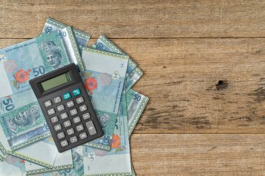 Hesap makinesi ve döküntü tahta arka planda bir tomar MYR banknotu. İş konsepti. Boşluğu kopyala.