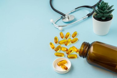 Mavi arka planda, fotokopi alanı olan balık yağı tableti. Sağlık ve Tıp Konsepti.