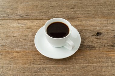 Tahta arka planda fotokopi alanı olan bir fincan kahve..