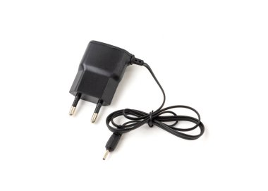 Beyaz arkaplanda eski ve modası geçmiş bir cep telefonu şarjı izole edilmiş.