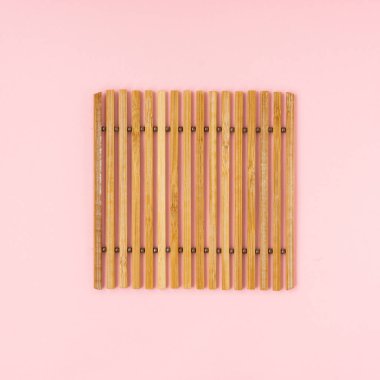 Açık pembe arka planda bambu çubukları.