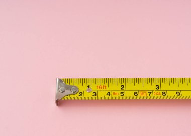Pembe arka planda santimetre ve inç olan şerit ölçülüyor.