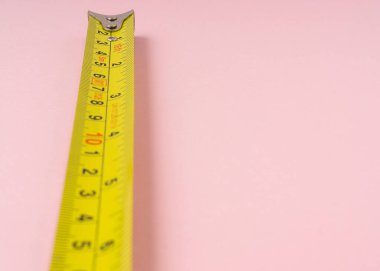 Pembe arka planda santimetre ve inç olan şerit ölçülüyor.