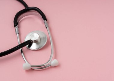 Açık pembe arkaplanda kopyalama alanı olan stetoskop.