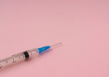 Açık pembe arkaplanda kopyalama alanı olan şırınga.