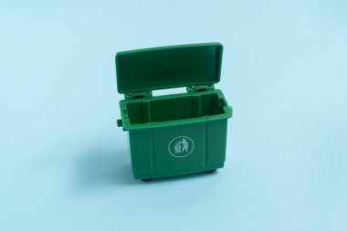 Açık mavi arkaplanda yeşil renkli çöp kovası