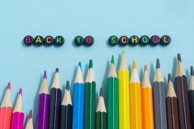 Açık mavi arkaplanda okula metin ile renkli kalem