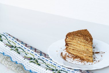 Beyaz bir tabakta, arka planda bir dilim pasta.