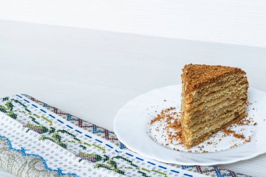 Bir dilim pasta, arka planda beyaz bir tabakta yakın plan.