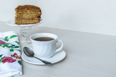 Beyaz çay ve kaşık. Arka planda bir parça ballı kek. Yatay fotoğrafçılık