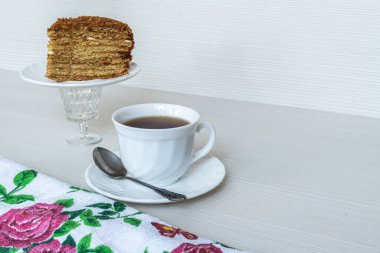 Beyaz çay ve kaşık. Bir parça ballı kek.