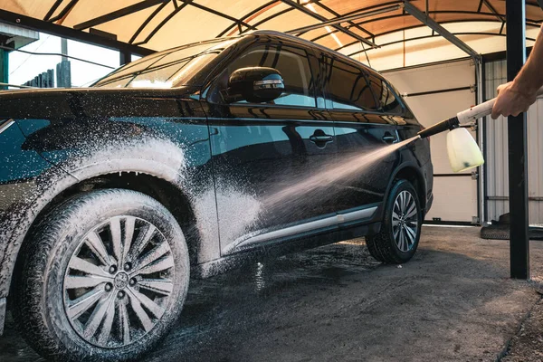 Car wash. Applying shampoo to a black car.