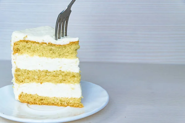 Een Vork Een Stuk Vanille Boterroom Cake Links Witte Achtergrond — Stockfoto