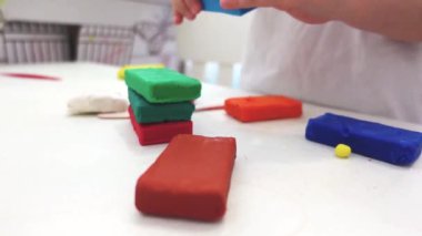 Çocukların ellerinin, çocukların yaratıcılığı ile ilgili yavaş çekim videolarından şekillendirme ve inşa etme videolarına yakın çekim. Beyaz arkaplanda çocuk gelişimi için ev etkinliği