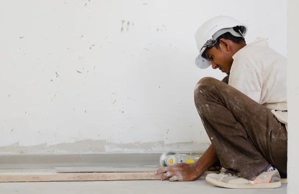 Travailleur étranger coupant du bois sur chantier — Photo