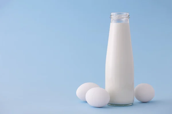 Milch und Eier auf blauem Hintergrund — Stockfoto