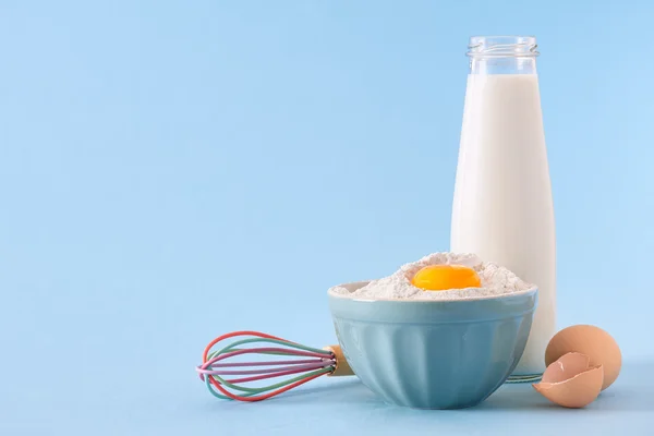 Молочная бутылка, яйца и миска с мукой — стоковое фото