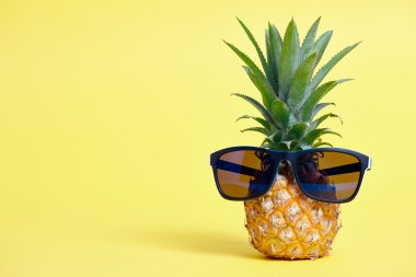 Ananas sarı arka plan üzerinde güneş gözlüğü ile