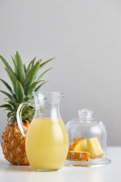 Jarro de vidro com suco de abacaxi e frutas na mesa — Fotografia de Stock