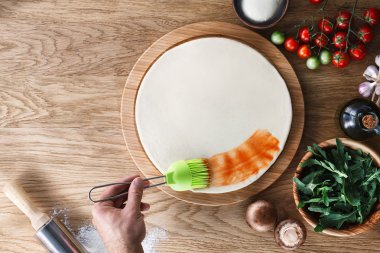 Pizzaya domates sosu serpiyorum.