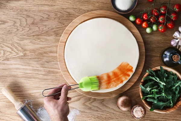 Pizzaya domates sosu serpiyorum.