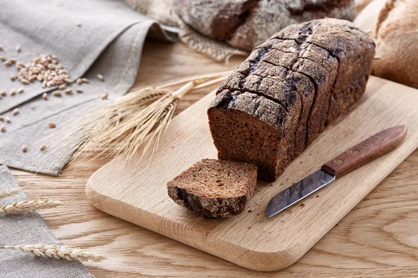 나무 테이블에 검은 빵을 슬라이스 — 스톡 사진