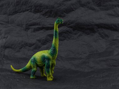 Esmer arka planda plastik oyuncak dinozor.