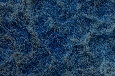 Aşındırıcı mavi bir temizleme yastığı yüzeyinin detaylı makro görüntüsü. Karışık sentetik lifler, soyut arka planlar veya hijyen ve maddeyle ilgili tasarımlar için ideal kaba ve düzensiz bir doku oluştururlar.