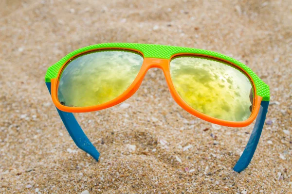 Colorful children sunglasses on the beach — Stock Photo, Image