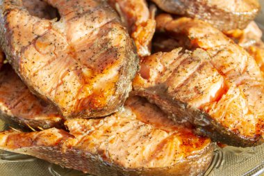 Izgara kırmızı alabalık bifteği cam tabakta yatıyor.