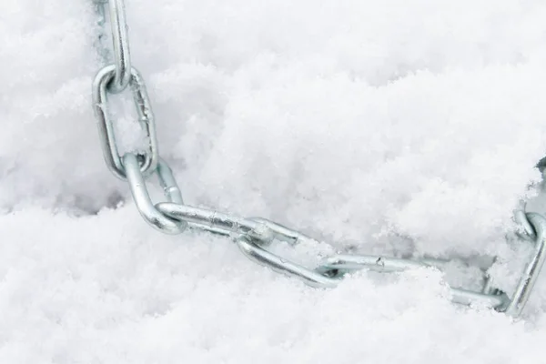 A metal chain lies on the snow in winter