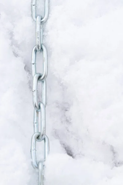 A metal chain lies on the snow in winter