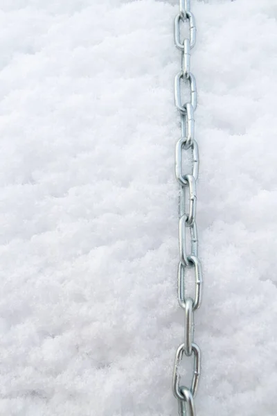 A metal chain lies on the snow in winter