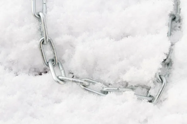 A metal chain lies on the snow in winter