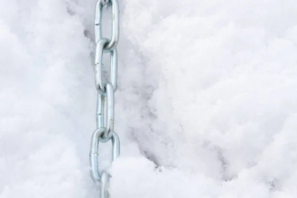 A metal chain lies on the snow in winter