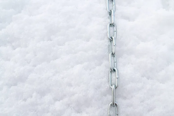 A metal chain lies on the snow in winter