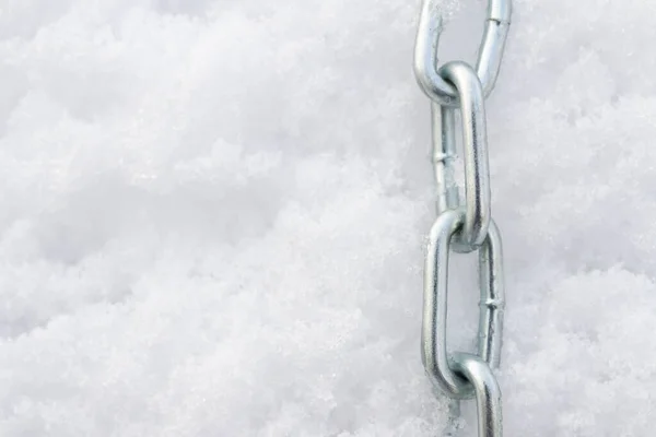 A metal chain lies on the snow in winter