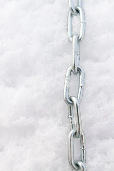 A metal chain lies on the snow in winter