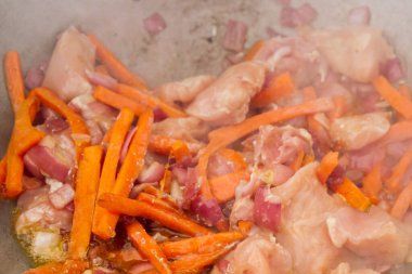 Tavuk parçaları ızgarada havuç ve kırmızı soğanla kızartılır.