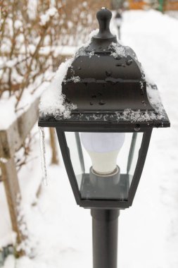 Kışın bahçede açık hava siyah feneri.